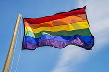 Rainbow flag waving over blue sky background